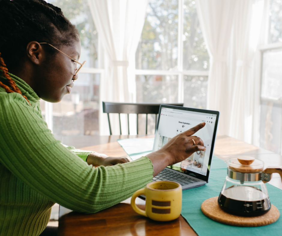 woman-in-green-sweater-at-kitchen-table-pointing-to-laptop