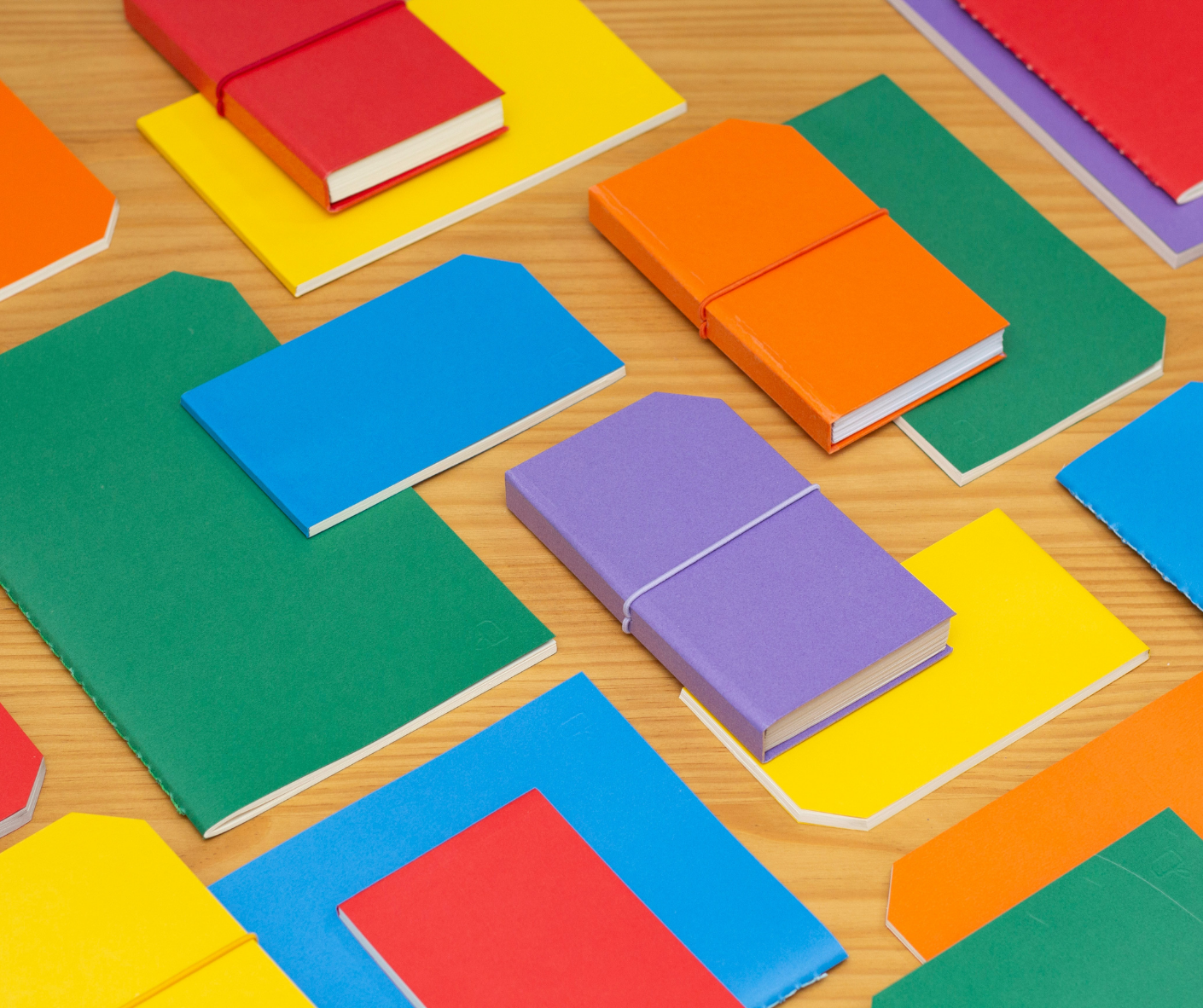 colorful-notebooks-and-folders-on-woodgrain-desk